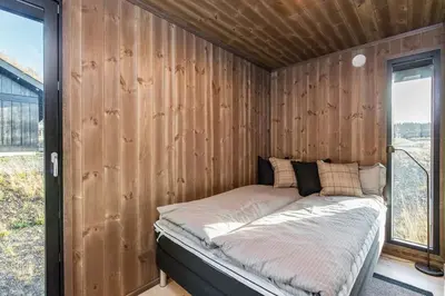 a bed in a room with a wooden wall at Modern cabin Hafjell high standard ski-in out in Hafjell