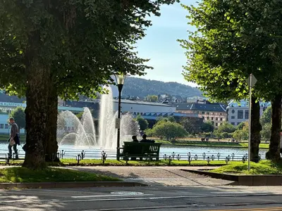 two people sitting on a park bench in front of a fountain at Lake view apartment in center of Bergen - 3 bedrooms in Bergen