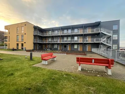 two red benches in front of a building at Attraktiv utsiktsleilighet in Ranheim
