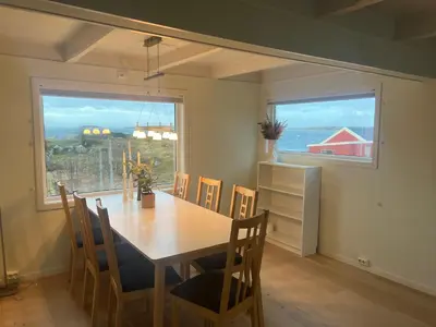 a dining room with a table and chairs and a window at Idyllisk perle ved sjøen! in Frøya