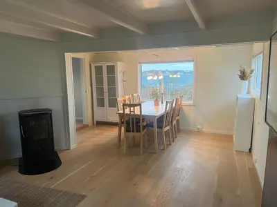a dining room with a table and chairs and a window at Idyllisk perle ved sjøen! in Frøya