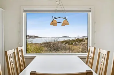 a dining room with a table and a large window at Idyllisk perle ved sjøen! in Frøya