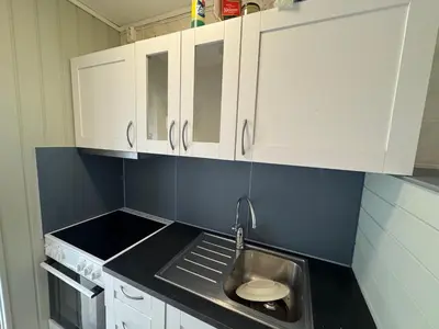 a small kitchen with a sink and white cabinets at Small apartment in Elnesvågen in Svinøya