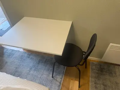 a white desk with a black chair next to a bed at Small apartment in Elnesvågen in Svinøya
