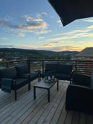 a patio with couches and a table on a deck at Delicate and new apartment in quiet surroundings in Trondheim