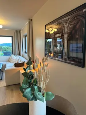a living room with a couch and a vase with flowers at Delicate and new apartment in quiet surroundings in Trondheim