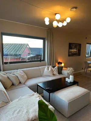 a living room with a white couch and a large window at Delicate and new apartment in quiet surroundings in Trondheim