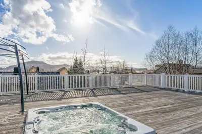 a hot tub on a deck with a fence at Casa Knott 4 Bedroom in Ulstein