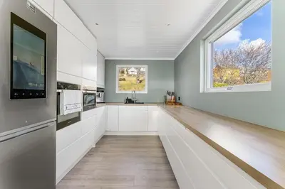 a kitchen with white cabinets and a large window at Casa Knott 4 Bedroom in Ulstein