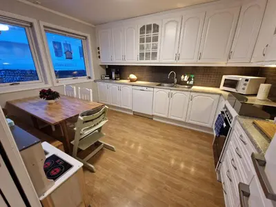 a kitchen with white cabinets and a wooden table at Granåsen World Championship Stay Walk to Ski Arena in Trondheim