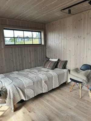 a bedroom with a bed and a chair and a window at Eksklusiv hytte Musdalsseter in Mo