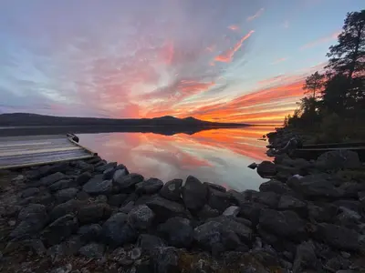 a sunset over a body of water with rocks at Family cabin by the lake at Haugen, Femundsmarka in Elga