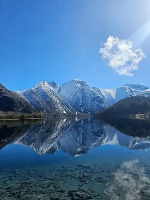 a view of a mountain reflecting in a lake at timber cabin Eresfjord med båt til leie in Øverås