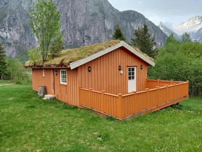 a small house with a grass roof on a field at timber cabin Eresfjord med båt til leie in Øverås