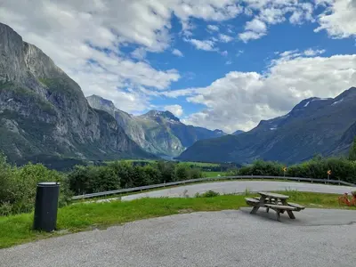 a picnic table sitting next to a road with mountains at timber cabin Eresfjord med båt til leie in Øverås