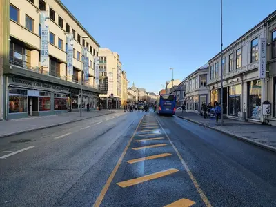 a bus driving down a city street with buildings at Delicate Central Apartment Trondheim in Trondheim