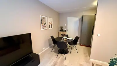 a living room with a table and chairs and a television at Delicate Central Apartment Trondheim in Trondheim