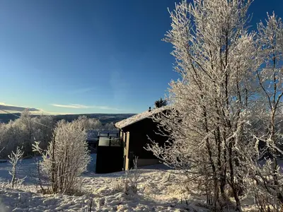 a cabin covered in snow with trees in the foreground at New modern cabin in Beitostølen in Beitostøl