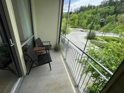a balcony with two chairs and a table and a street at Cozy 1-bedroom in quiet Ilsvika in Trondheim