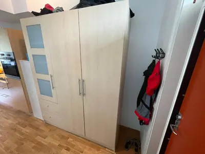 a closet with white cabinets and red clothes hanging at Cozy 1-bedroom in quiet Ilsvika in Trondheim