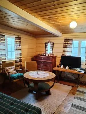 a living room with a table and a desk at Idyllic cabin at Bjaarvatnet in Tuddal