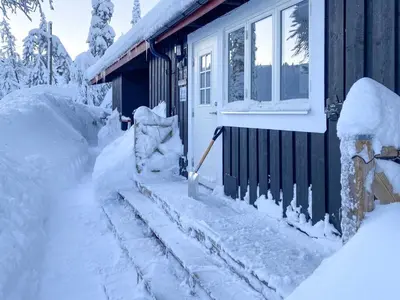 a house covered in snow with a shovel next to it at Trysilfjellet Nord 1071B in Trysil