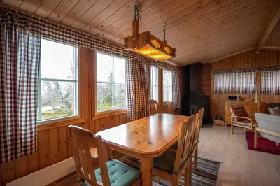 a dining room with a wooden table and some windows at Trysilfjellet Nord 1017 in Trysil