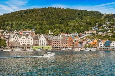 a boat in the water in front of a city at DINBNB Apartments Private terrace l 700 m to Bryggen l Modern in Bergen