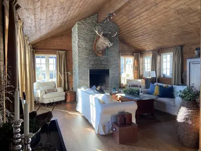 a living room with white furniture and a stone fireplace at Wonderful Ski-In, ski-out Cabin at Kvitfjell in Strande