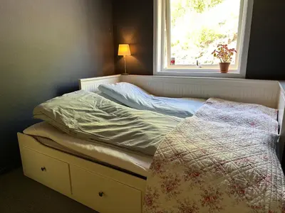 a unmade bed with a window in a bedroom at Granåsen ski-VM in Trondheim
