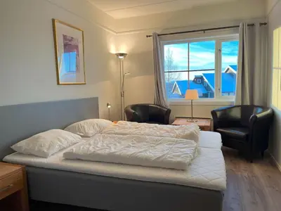 a bedroom with a bed and two chairs and a window at Bitihorn fjellbris in Beitostøl