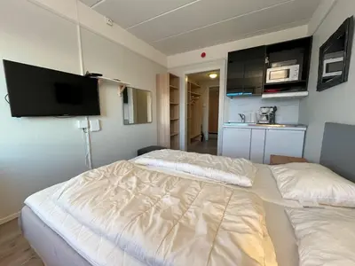 a room with two beds and a tv on the wall at Bitihorn fjellbris in Beitostøl