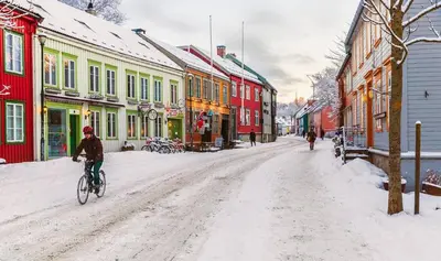 a person riding a bike down a snow covered street at Beautiful and central apartment for rent during Ski WC 2025 in Trondheim