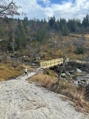a person walking across a bridge on a dirt road at Norefjell! Newly built cabin with stunning view in Noresund