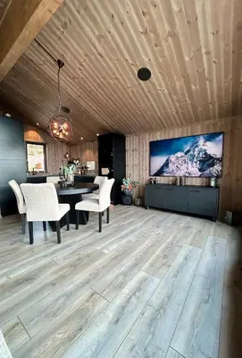 a dining room with a large tv and a table and chairs at Norefjell! Newly built cabin with stunning view in Noresund