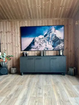 a television on a wall with a snow covered mountain at Norefjell! Newly built cabin with stunning view in Noresund