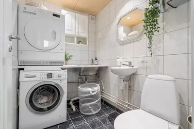 a bathroom with a washing machine and a sink at Spacious and Peaceful Home with a Private Gym in Trondheim