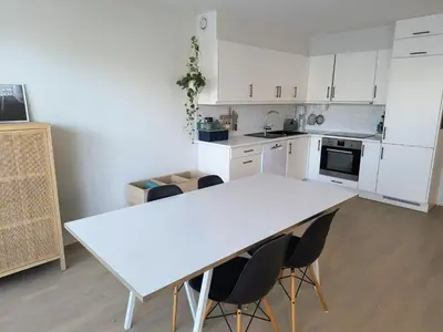 a white kitchen with a white table and chairs at Romslig og pen leilighet - sentral beliggenhet in Charlottenlund