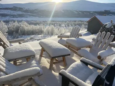a group of chairs covered in snow with the sun in the background at Koselig hytte med uthus på vakre Dovrefjell in Dovre