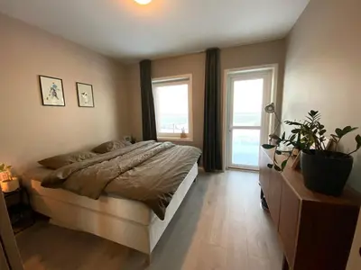 a bedroom with a large bed and two windows at Hus til leie under VM 2025 in Trondheim