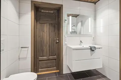 a bathroom with a toilet and a wooden door at Very central and fresh apartment 4 bedr, 10p 2 floors, sauna, ski in and out in Trysil