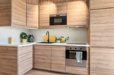 a kitchen with wooden cabinets and a stainless steel oven at Lys og koselig leilighet in Trondheim