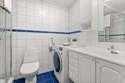 a white bathroom with a washing machine and a sink at Koselig leilighet på Møllenberg in Trondheim