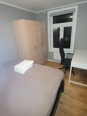 a bedroom with a bed and a desk and a chair at Koselig leilighet på Møllenberg in Trondheim