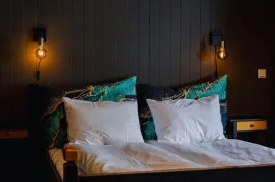 a bed with white sheets and pillows in a room at Bergmannshuset in Løkken