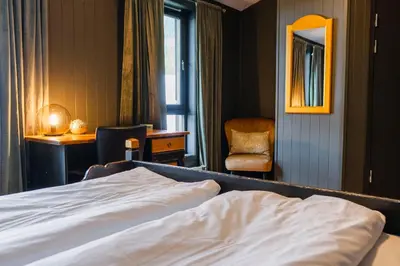 a bedroom with a bed and a chair and a mirror at Bergmannshuset in Løkken