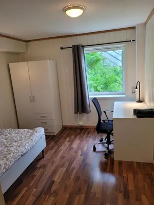 a bedroom with a bed and a desk and a window at 4 and 6 bedroom apartments Ski WC in Trondheim