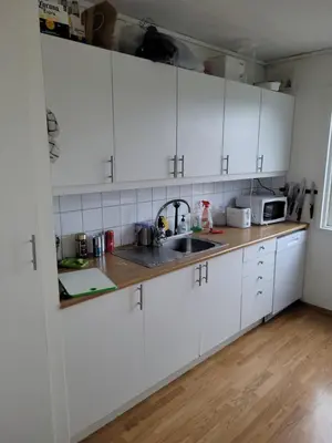 a kitchen with white cabinets and a sink at 4 and 6 bedroom apartments Ski WC in Trondheim