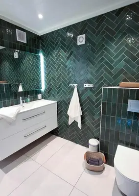 a bathroom with green tiled walls and a toilet at ThePearl in Sel