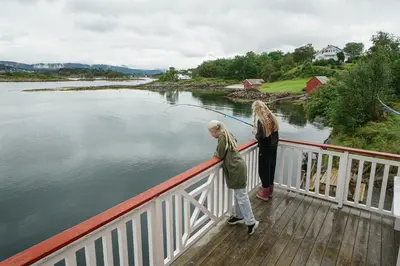 two people standing on a bridge over a body of water at Eget hus i sjøkanten ved fjorden in Langevåg